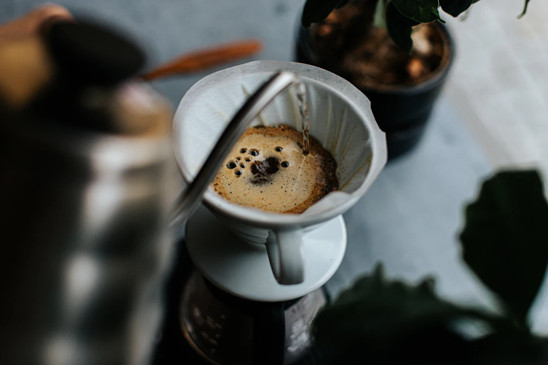 Café preparado en método filtrado V60 goteando dentro de una taza blanca